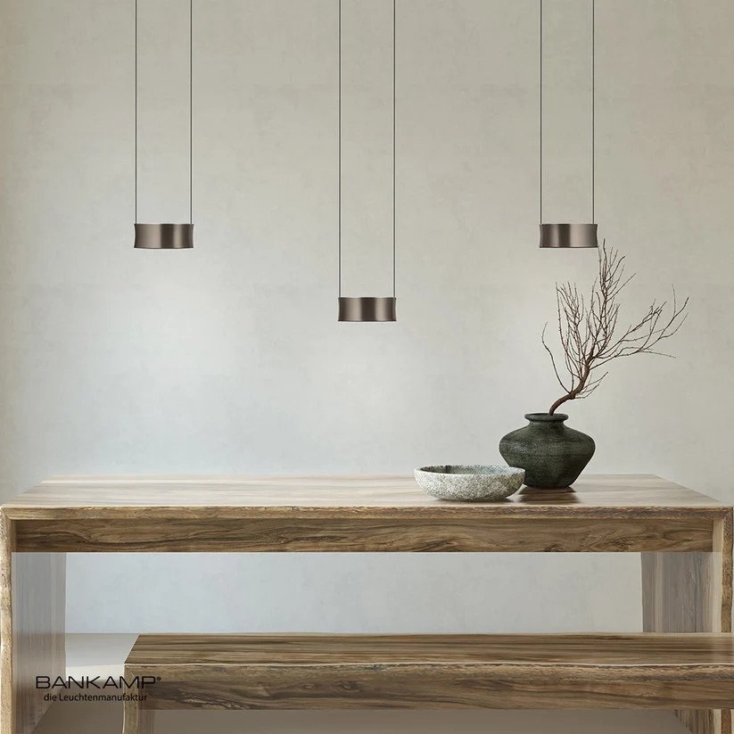 Bankamp Impact hanglamp 3-delig boven een houten eettafel Bankamp Impact hanglamp 3-delig boven een houten eettafel met drie verstelbare lichtarmaturen