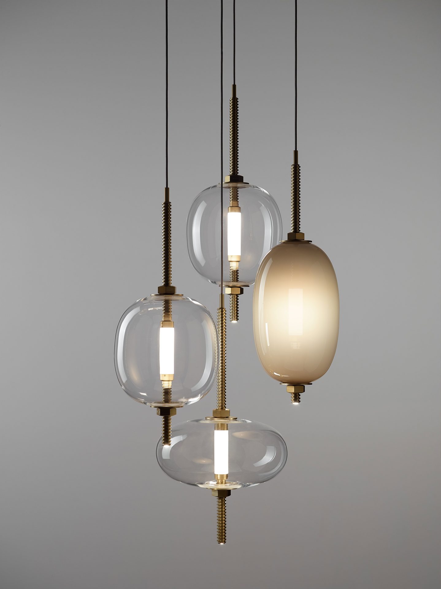 Under Pressure – vier hanglampen in verschillende glasvormen Brokis Under Pressure hanglamp compositie met vier pendels in transparant en parelgrijs opaalglas, afgewerkt met geborsteld champagnekleurig metaal