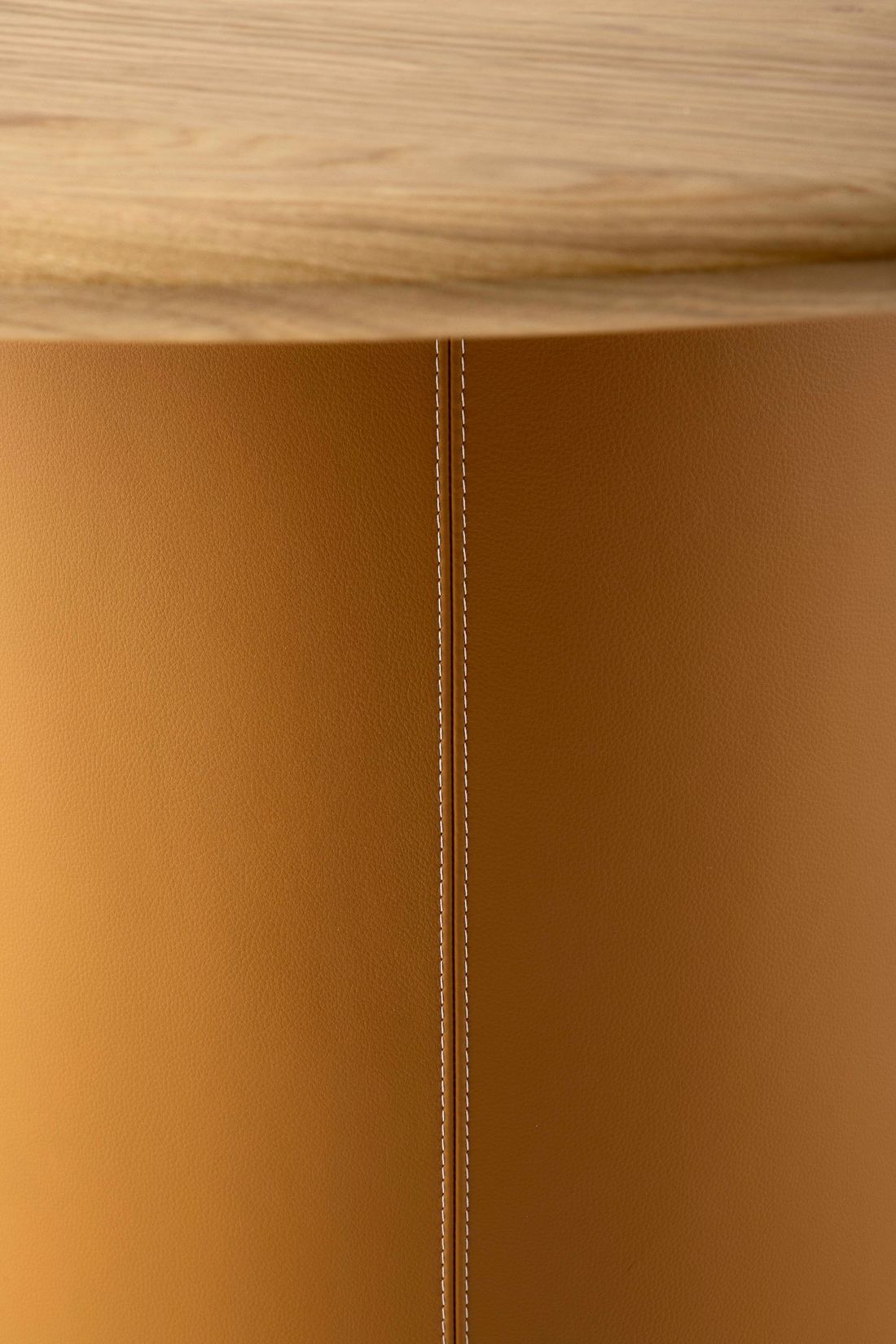 Eikenhout met bruin-oranje leer Leolux Tilar ronde eettafel met eikenhouten blad en bruinleren kolom met stiknaad