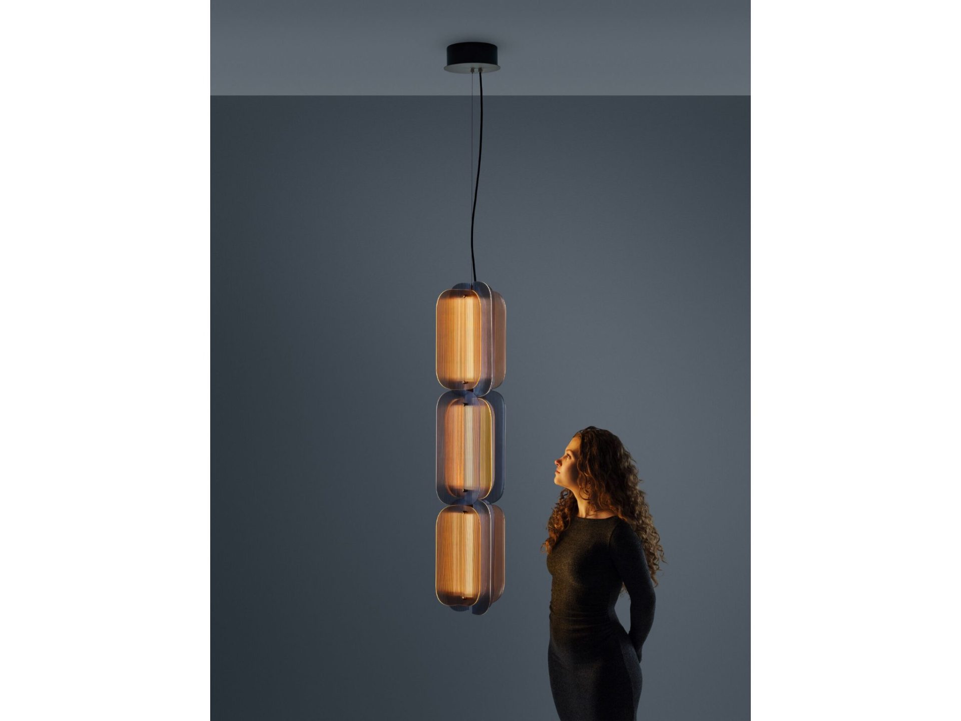 Quasar Fold 3 hanglamp design glas met drie lichtmodules Quasar Fold 3 hanglamp met drie lichtmodules van geribbeld glas naast een persoon